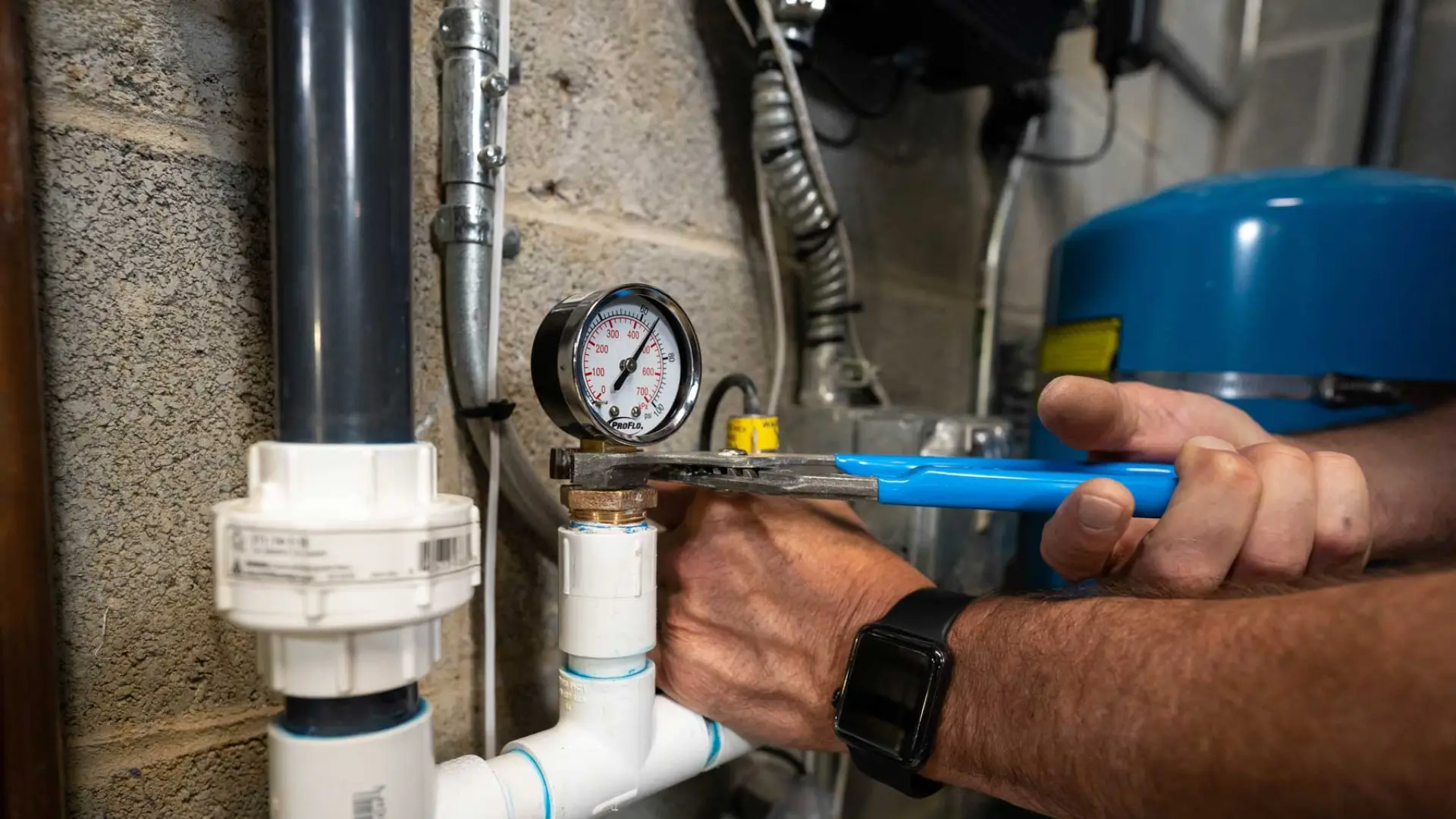 Un plombier utilisant un manomètre pour tester la pression d'eau au robinet d'un évier de cuisine